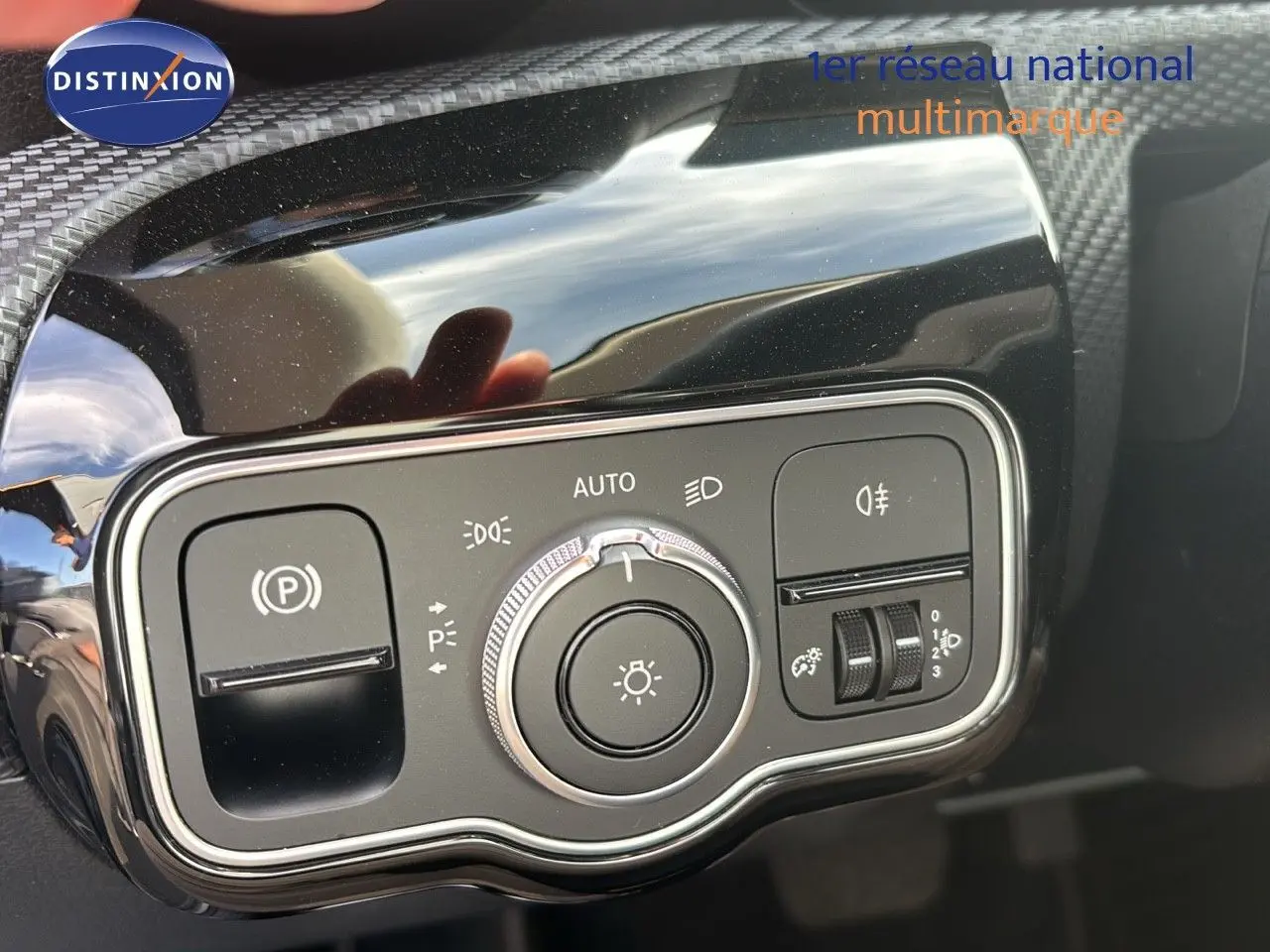 Gros plan sur le panneau de commande des phares et du frein à main électrique d'une Mercedes Classe A gris montagne métal.