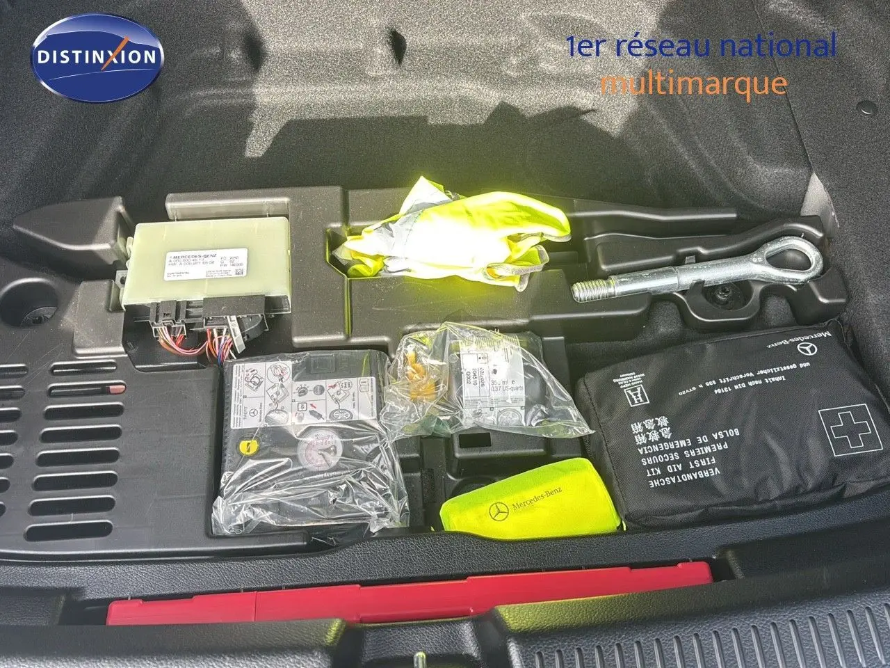 Coffre ouvert d'une Mercedes Classe A 200D gris montagne métal, montrant le kit de secours et outils rangés.