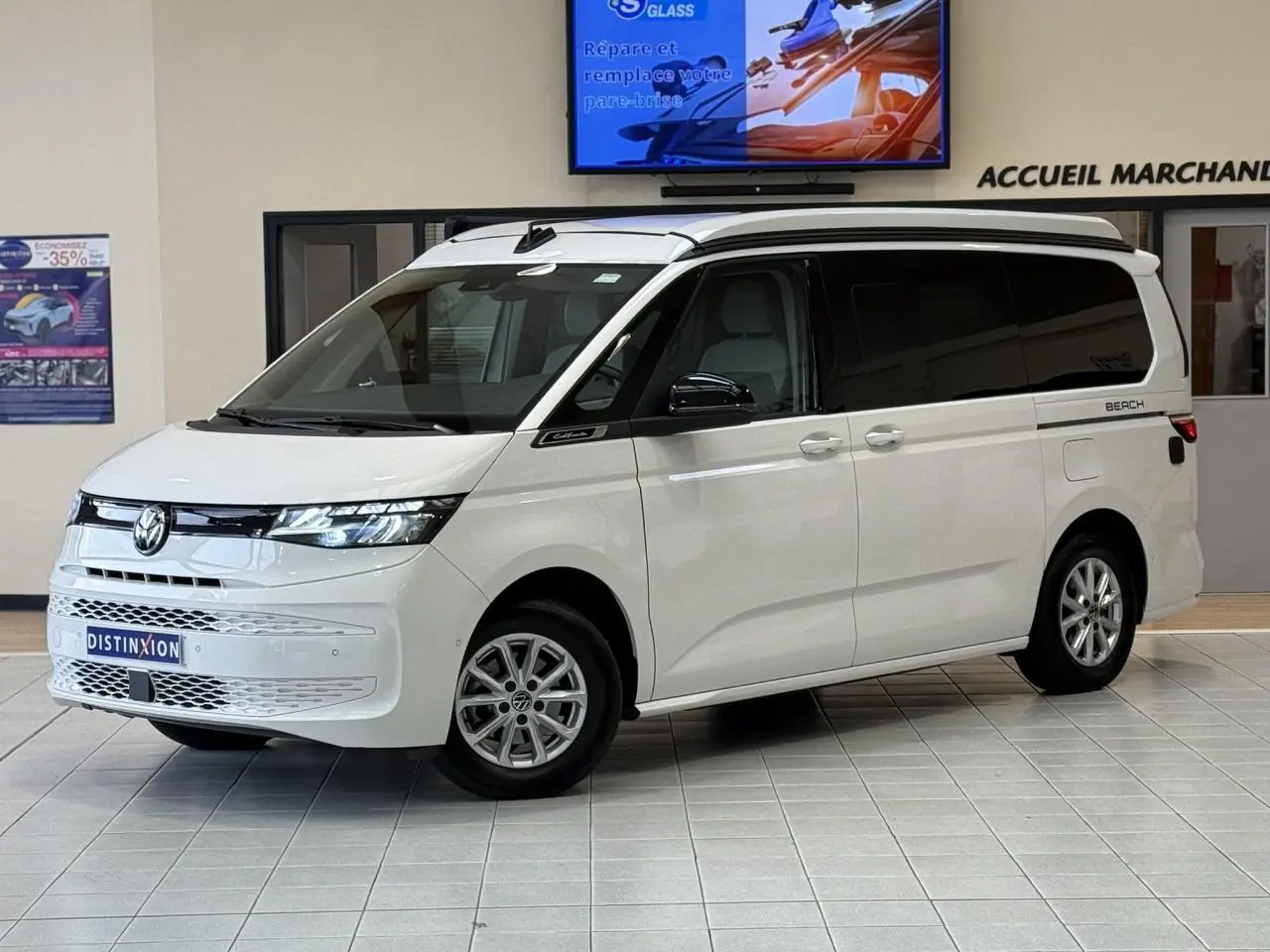 Volkswagen California T7 blanc Candy en 3/4 avant droit, avec vitres arrière teintées et toit relevable fermé.