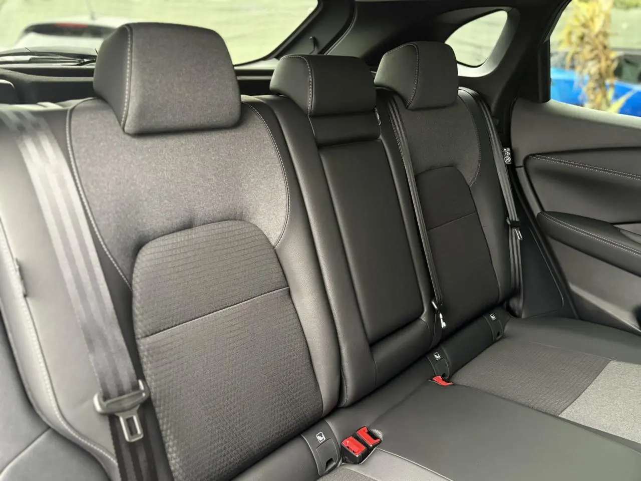 Vue latérale intérieure des sièges arrière noirs du Nissan Qashqai 2024, avec ceintures de sécurité visibles.