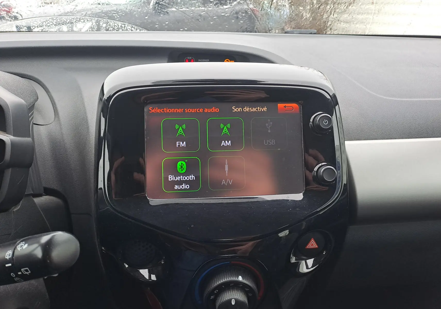 Vue rapprochée du tableau de bord de la Peugeot 108 bleu, avec écran tactile affichant les sources audio.