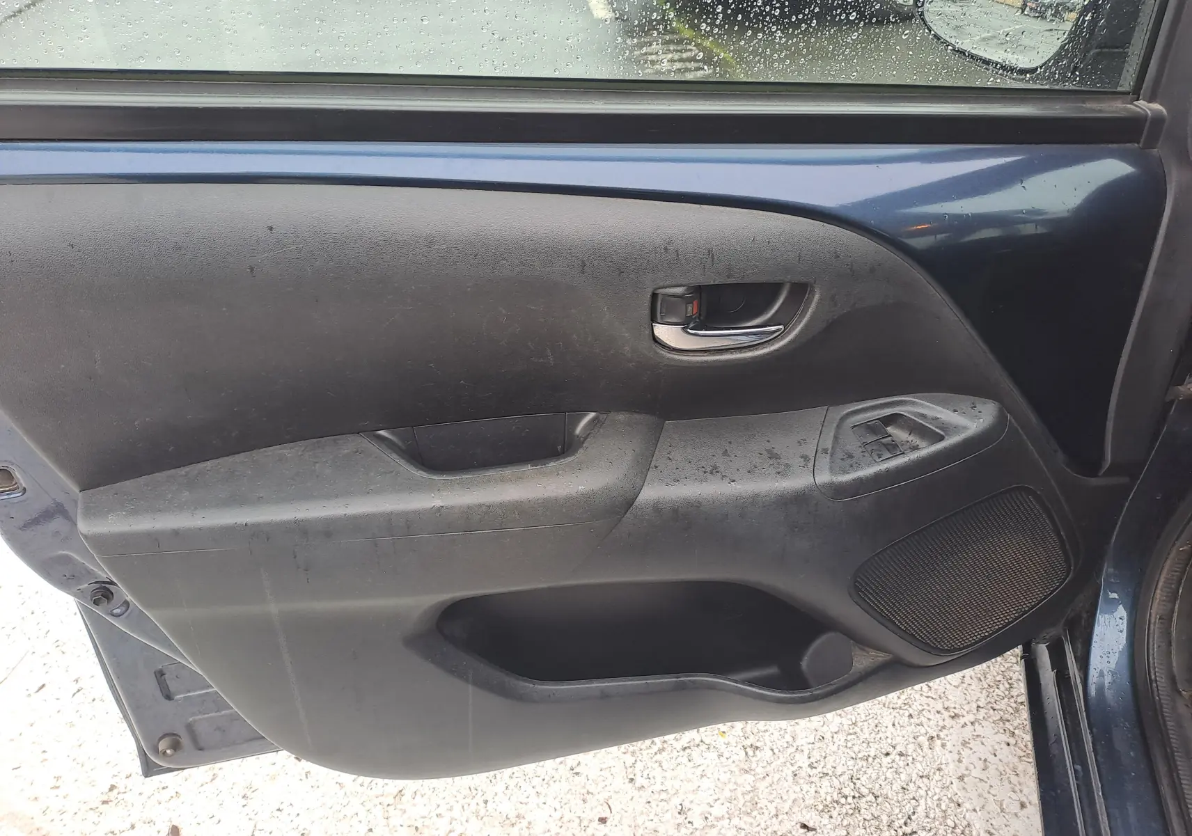 Vue rapprochée de la porte avant gauche bleue de la Peugeot 108 avec commandes de vitre et poignée intérieure chromée.