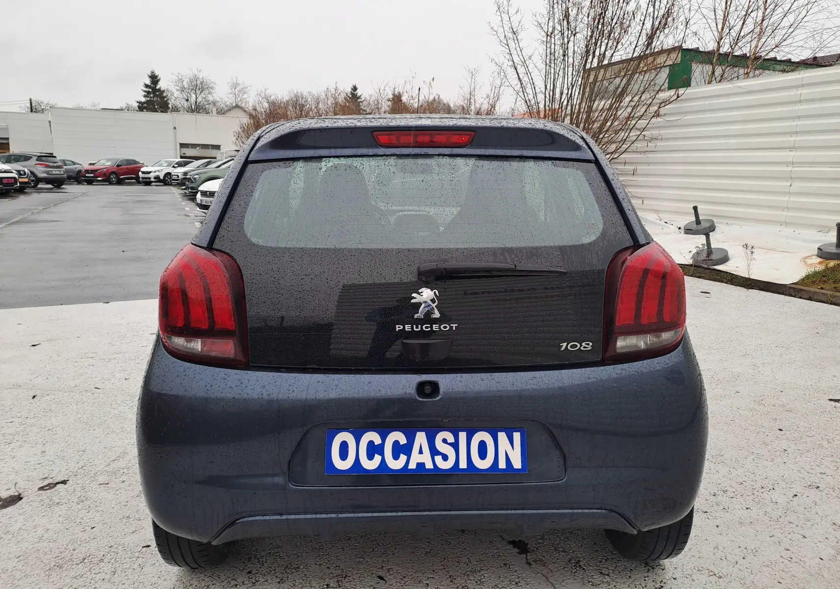 Vue arrière d'une Peugeot 108 bleu foncé 5 portes avec feux arrière rouges et plaque "OCCASION" visible.