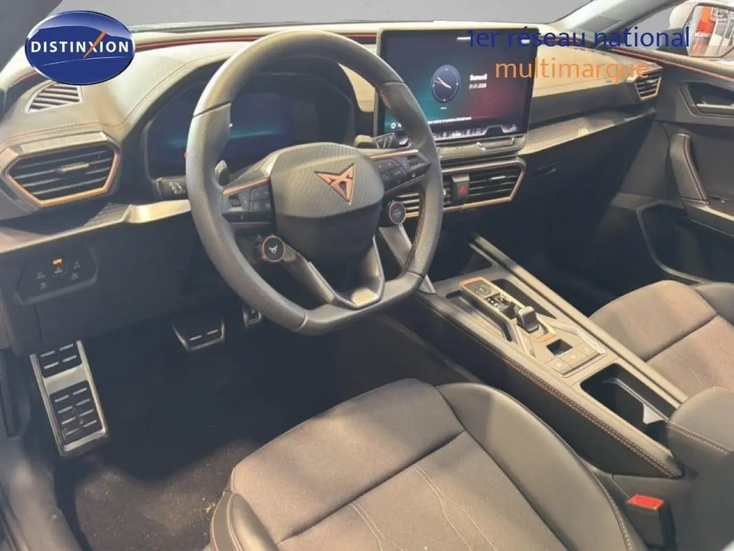 Intérieur de la CUPRA Leon ST 2025 vu côté conducteur, volant cuir avec logo, écran tactile et console centrale moderne.