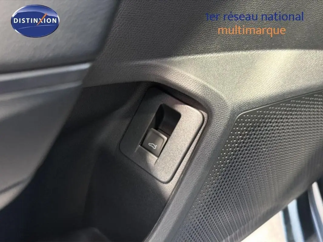 Détail du bouton d'ouverture de coffre sur la porte intérieure côté gauche d'une CUPRA Leon gris 2025.