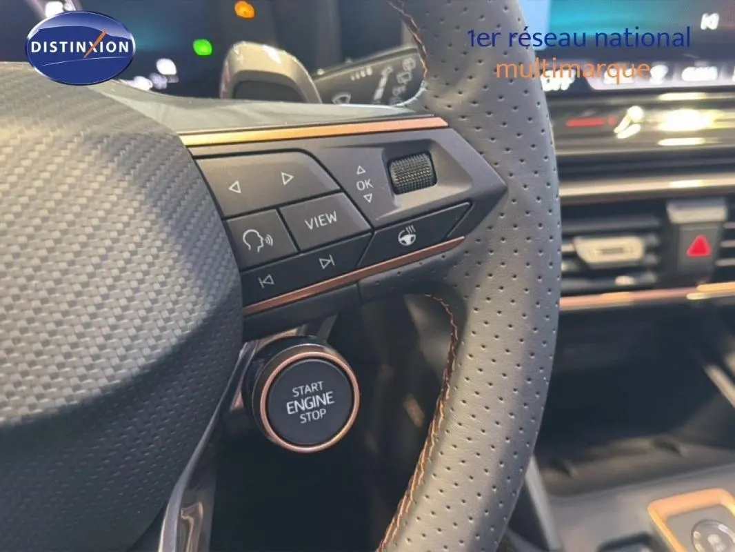 Gros plan sur le volant cuir perforé gris avec commandes intégrées et bouton start/stop du CUPRA Leon ST 2025.
