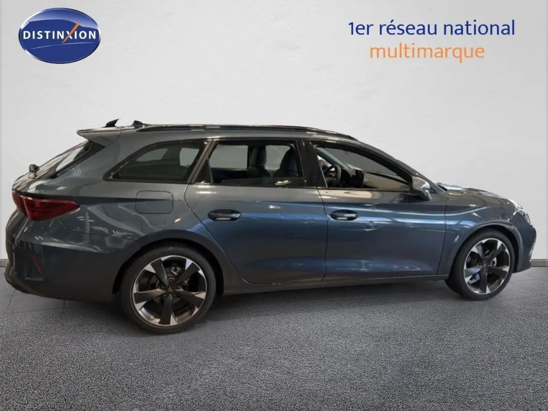 Profil droit d'une CUPRA Leon ST gris métallisé avec barres de toit et jantes aluminium distinctives.