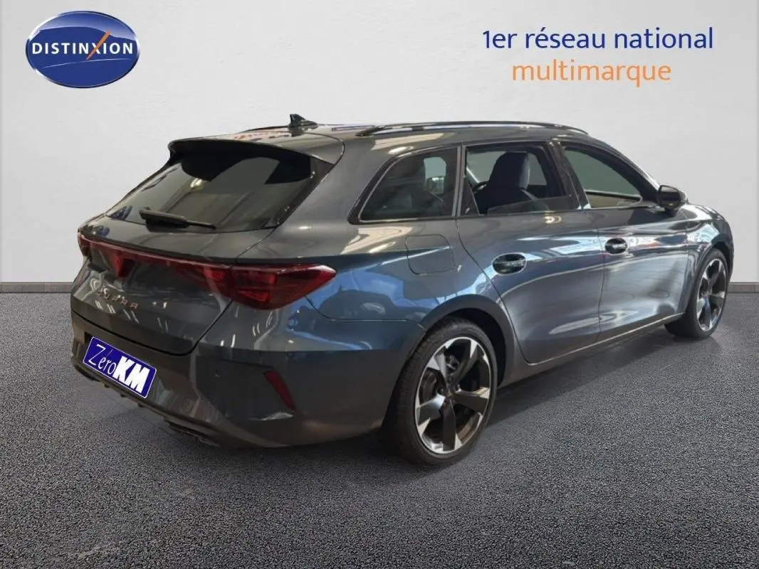 Vue 3/4 arrière droite d'une CUPRA Leon ST gris métallisé avec barres de toit et jantes aluminium.