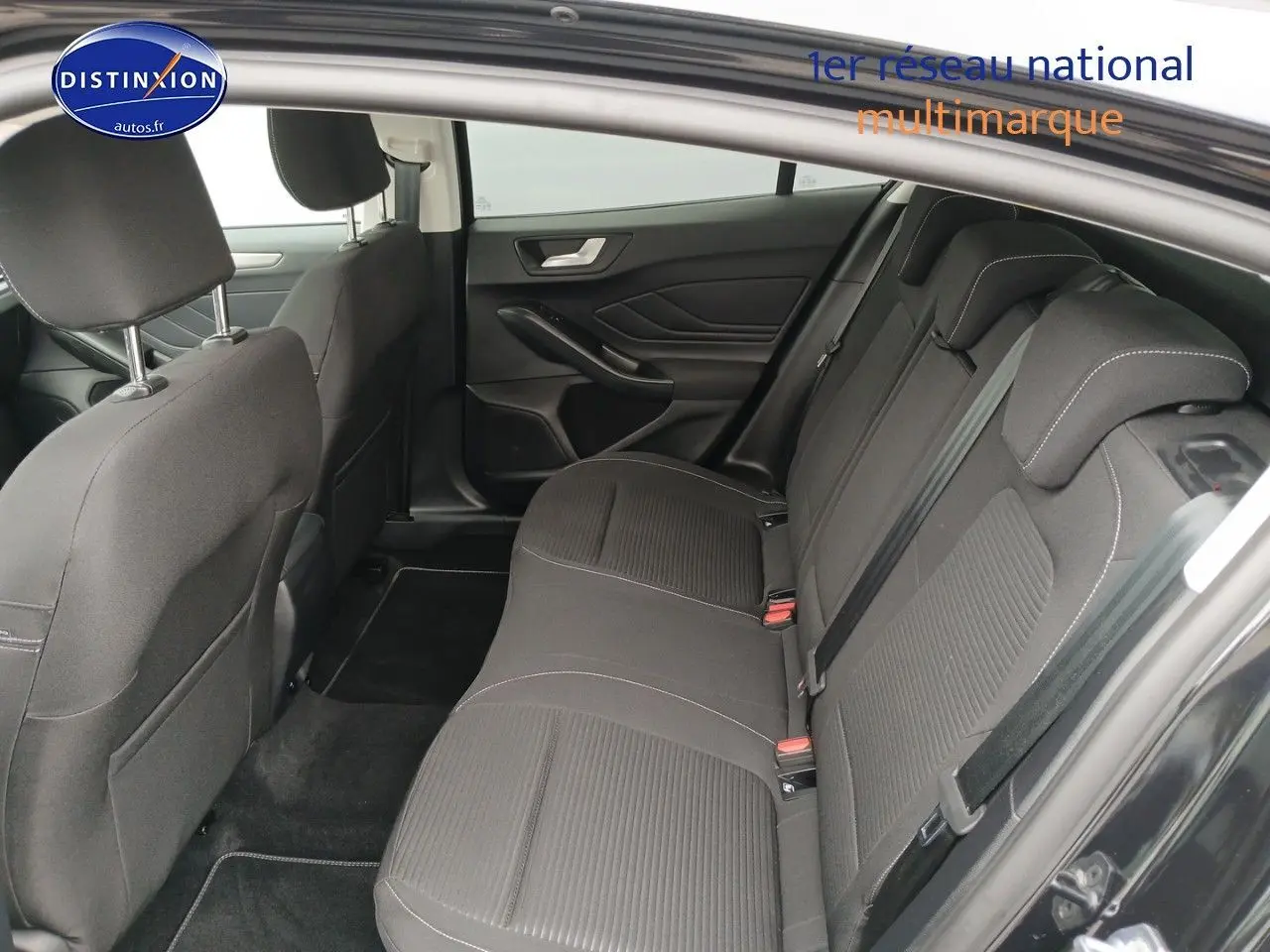 Vue intérieure côté droit montrant la banquette arrière en tissu noir avec appuie-têtes et ceintures de sécurité.