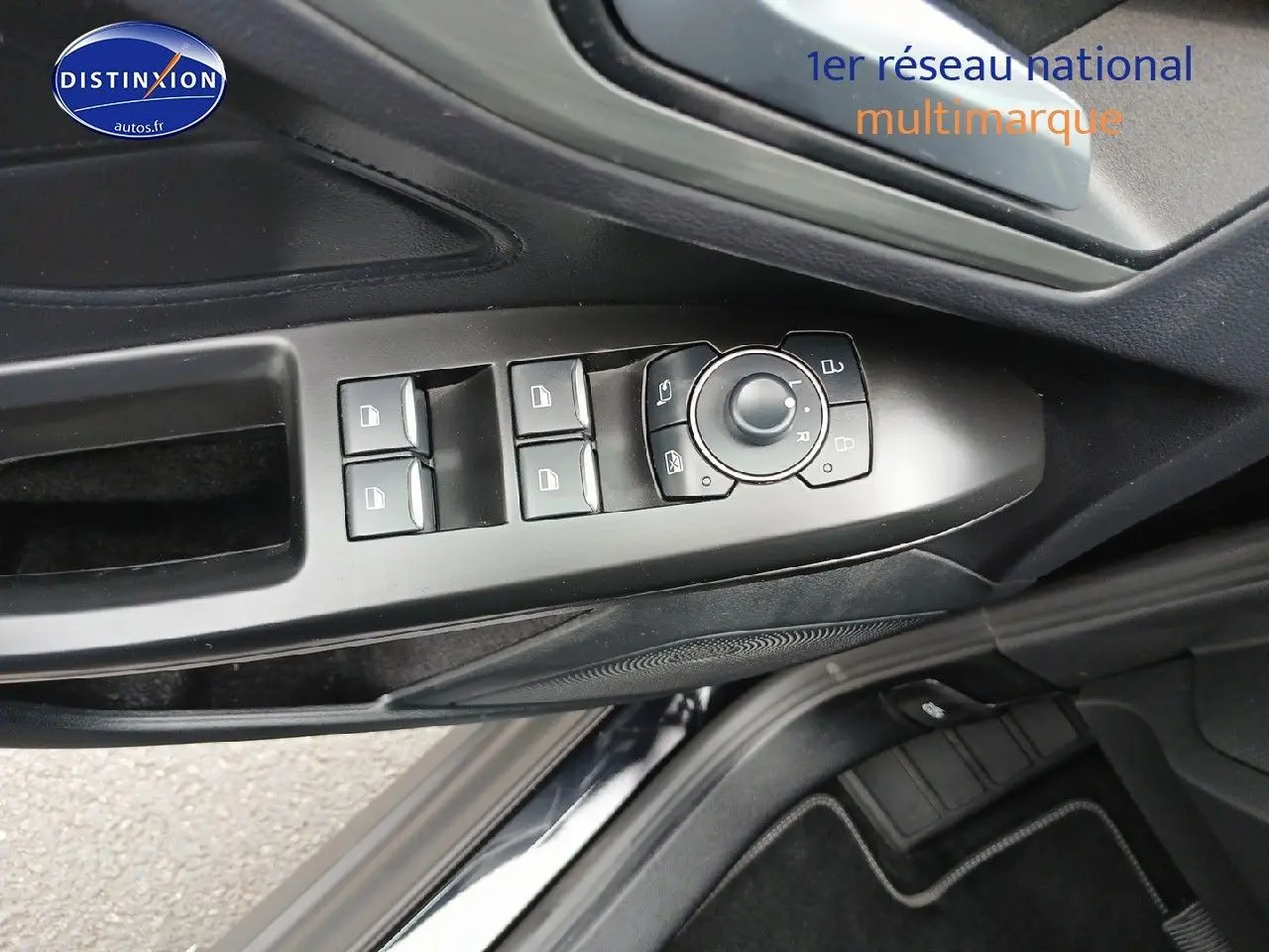 Vue rapprochée des commandes de lève-vitres et rétroviseurs sur la porte côté conducteur d’une Ford Focus noir Agate 2024.