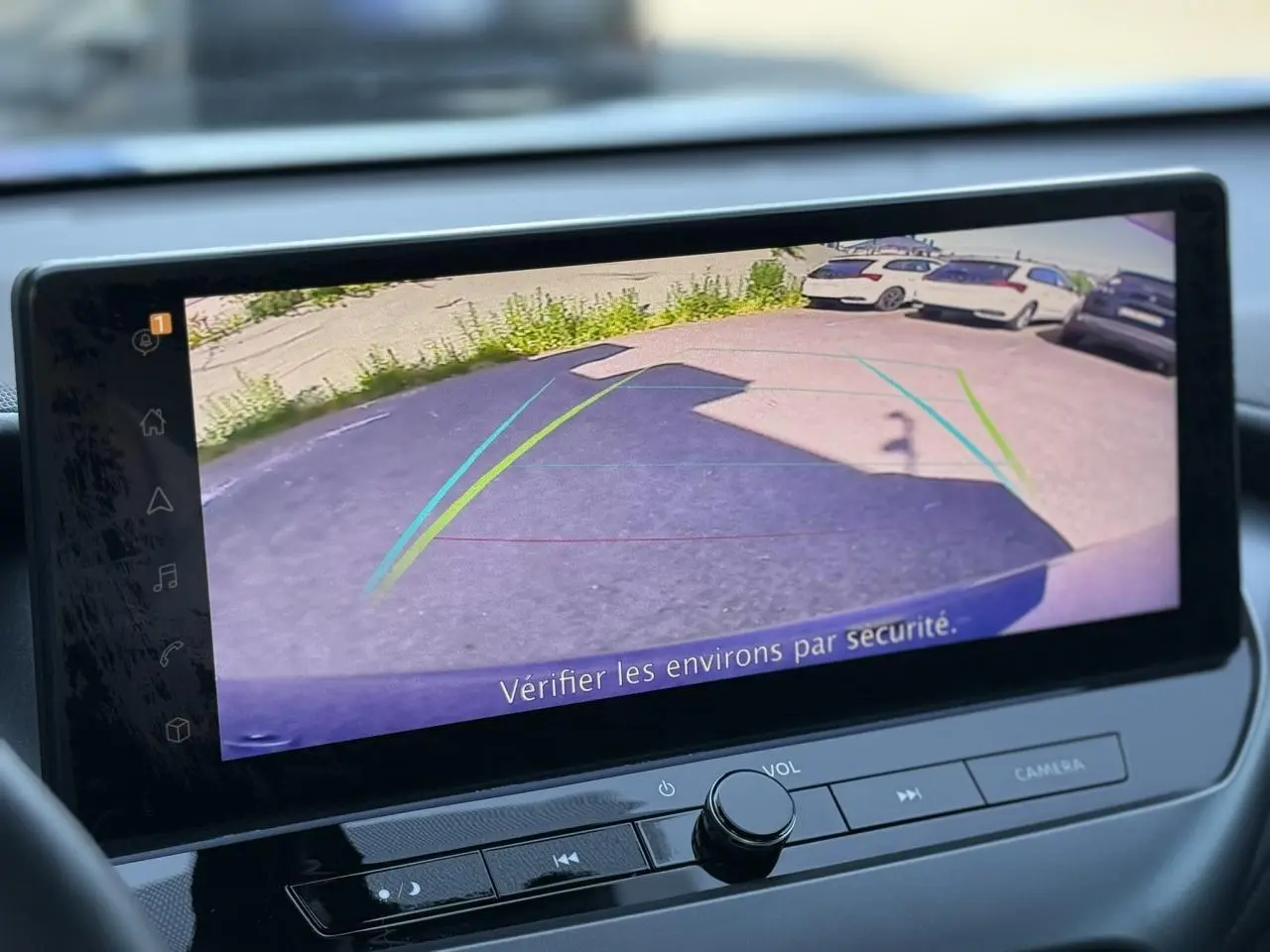 Écran tactile intérieur du Nissan Juke 2025 montrant la caméra de recul avec lignes d’aide au stationnement.