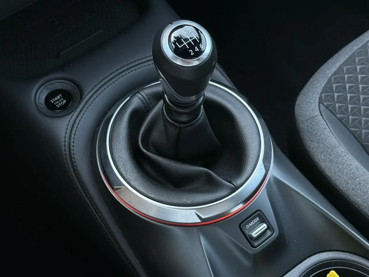 Gros plan sur le levier de vitesses manuel noir et argenté du Nissan Juke 2025 avec bouton Start/Stop et bouton D-Mode.