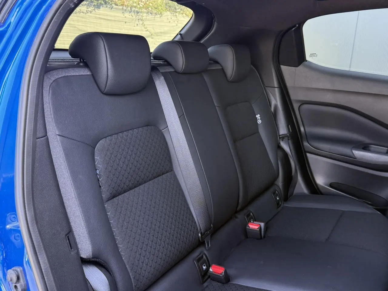 Vue intérieure sur la banquette arrière noire du Nissan Juke 2025, avec ceinture grise et sellerie mixte tissu/TEP.