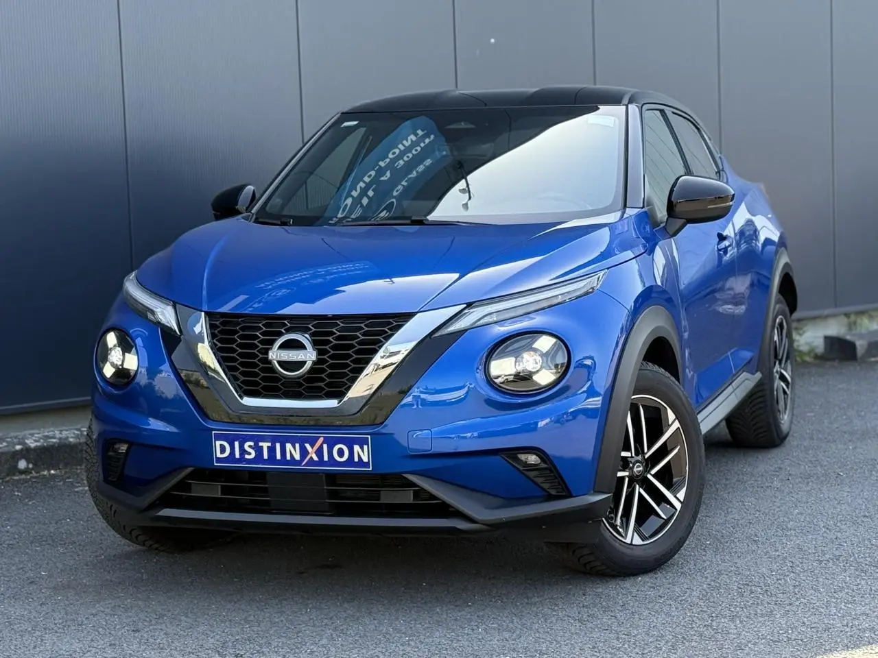Nissan Juke 2025 bleu magnétique avec toit noir, vue 3/4 avant mettant en valeur ses phares LED ronds et jantes alliage.
