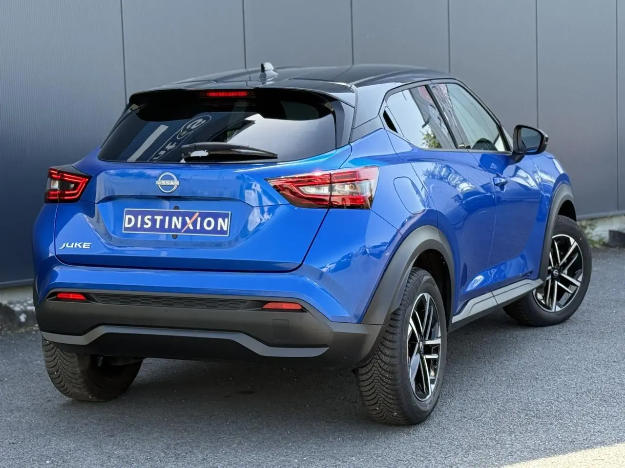 Vue 3/4 arrière droite du Nissan Juke 2025 bleu magnétique avec toit noir et jantes alliage 17 pouces.