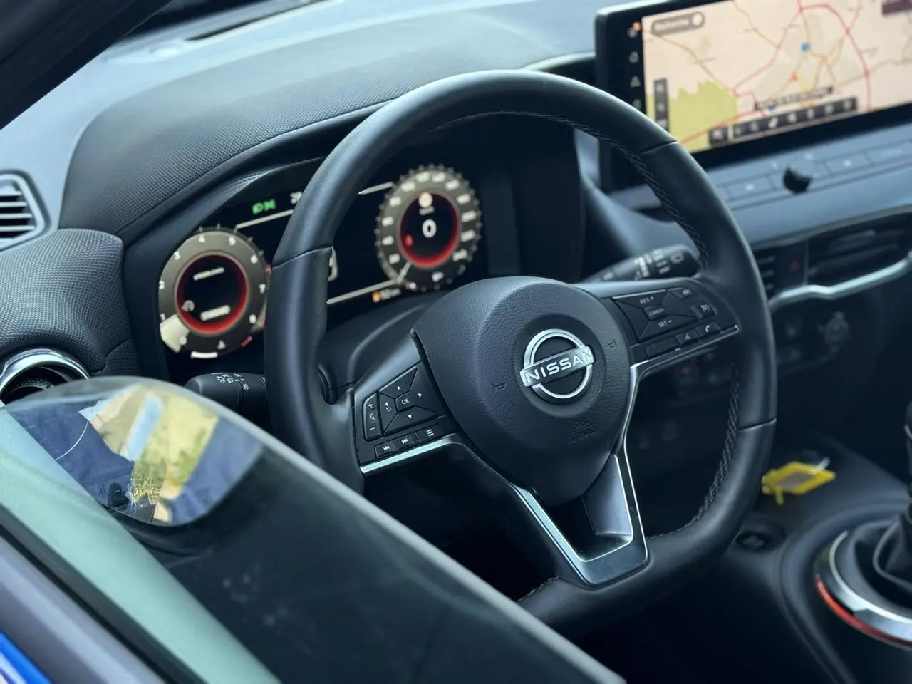 Vue rapprochée du volant noir et du tableau de bord digital du Nissan Juke 2025 avec écran tactile et commandes intégrées.