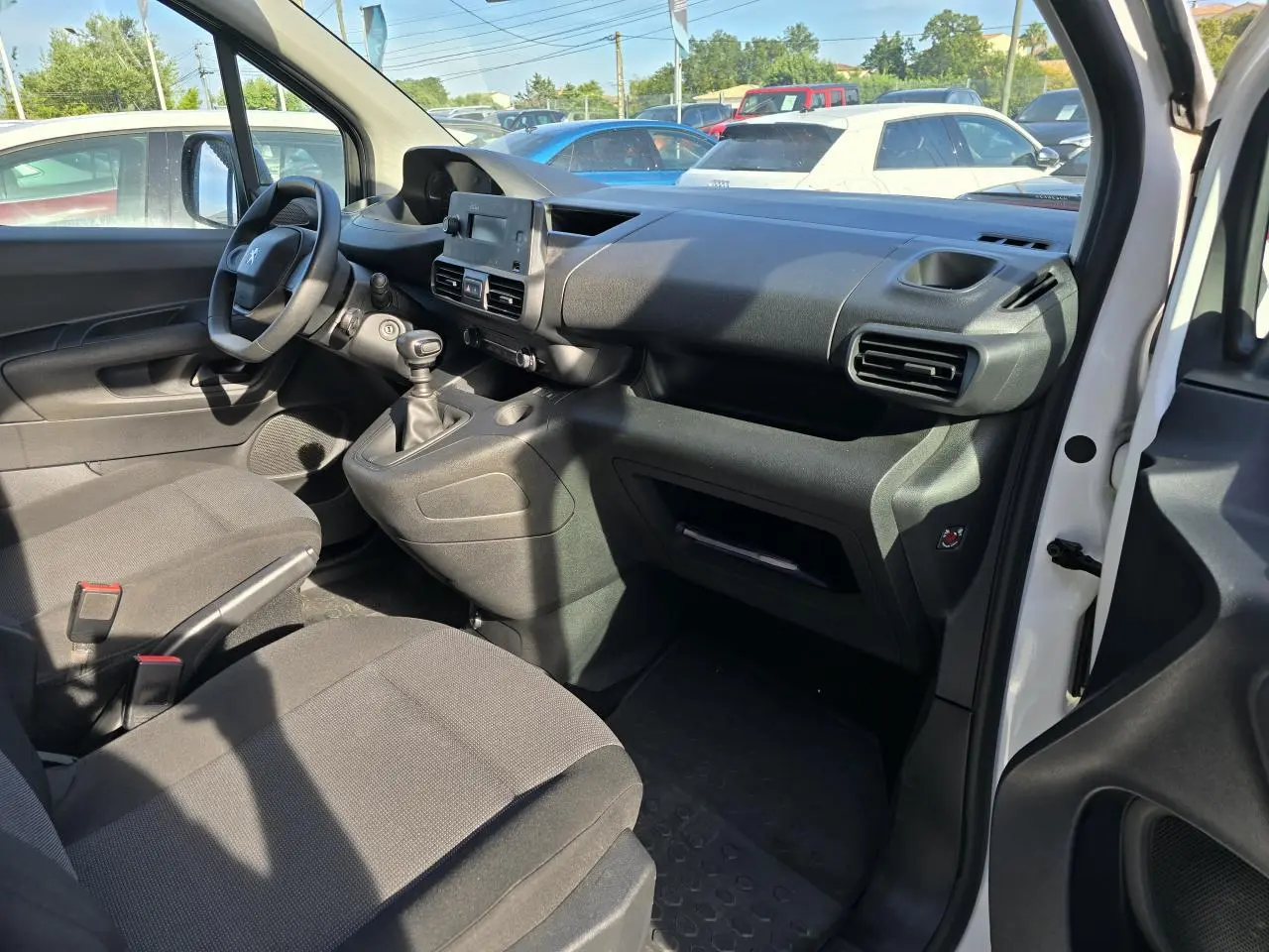 Vue intérieure côté conducteur du Peugeot Rifter blanc Banquise 2021, montrant le tableau de bord et la boîte manuelle.