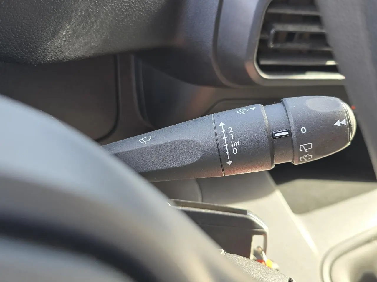 Gros plan sur la commande d’essuie-glace noire à gauche du volant dans l’habitacle du Peugeot Rifter blanc Banquise.