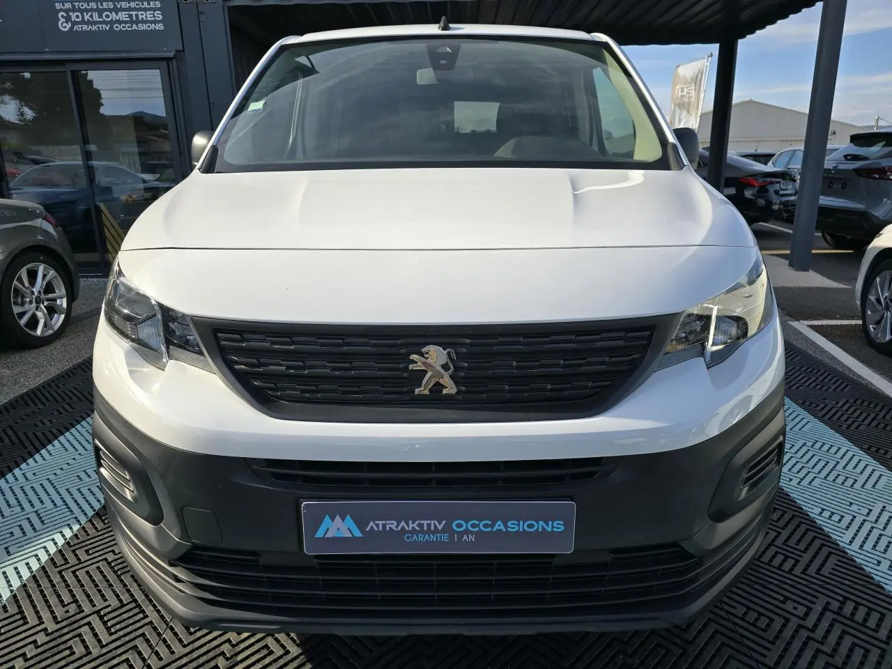 Vue frontale d'un Peugeot Rifter 1.5 BlueHDi blanc Banquise avec calandre noire et logo lion central.