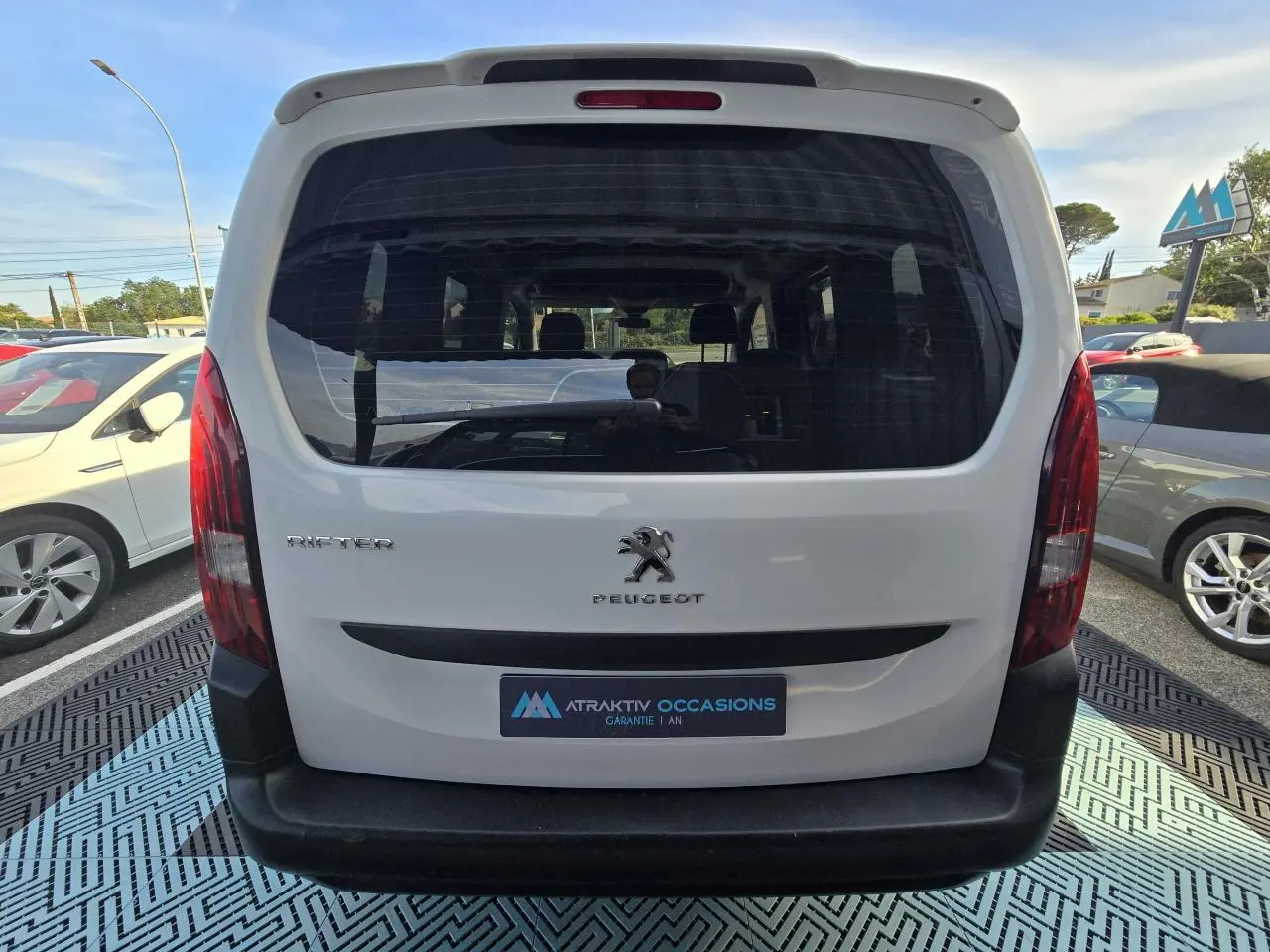 Vue arrière d'un Peugeot Rifter blanc Banquise 2021 avec hayon vitré et pare-chocs noir mat visible en extérieur.