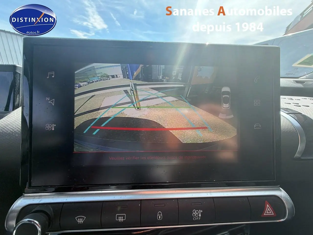 Écran tactile intérieur montrant la caméra de recul d'une Citroën C4 Cactus bleu métal, vue depuis le tableau de bord.