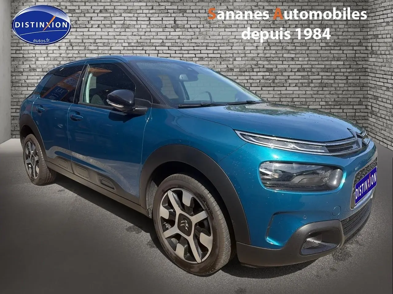 Citroën C4 Cactus bleu métal en 3/4 avant droit, avec jantes alliage et protections noires sur carrosserie.