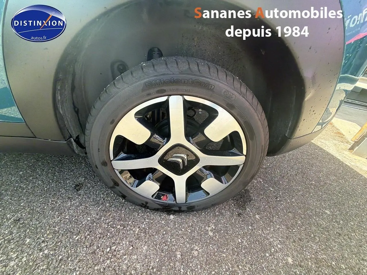 Gros plan sur la roue avant gauche d'une Citroën C4 Cactus bleu métal avec jante alliage bicolore.