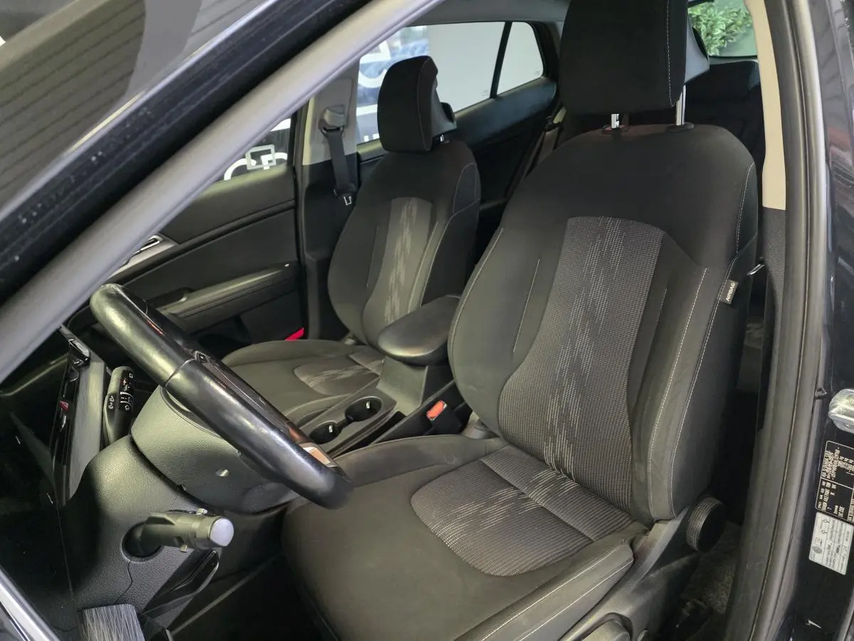Intérieur noir du Kia Sportage 2022, vue côté conducteur montrant sièges tissu et volant cuir.