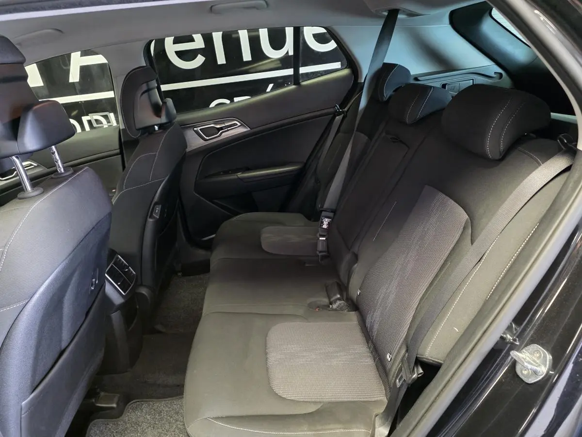 Vue intérieure côté droit sur la banquette arrière noire en tissu du Kia Sportage 2022 avec appuie-têtes et ceintures visibles.