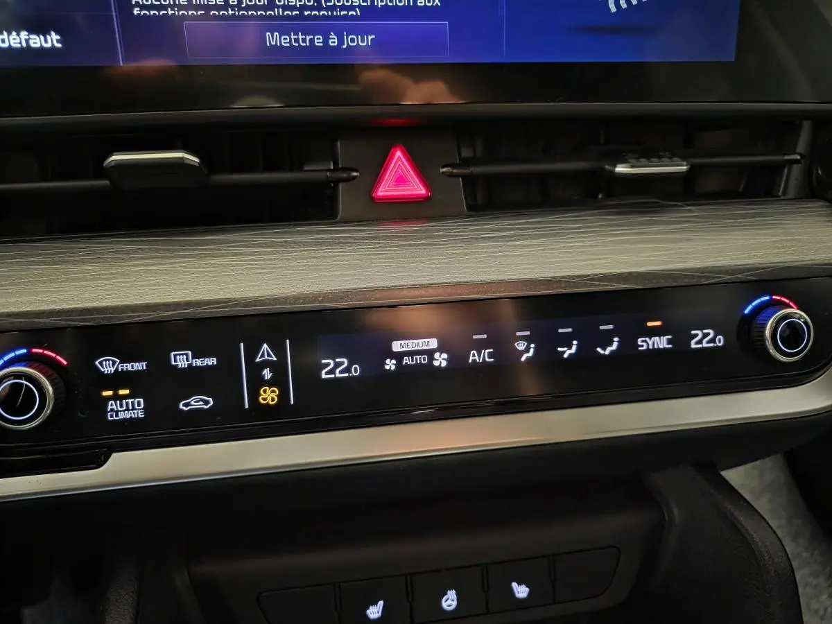 Vue rapprochée de la console centrale du Kia Sportage noir 2022, affichant la climatisation automatique et les commandes tactiles.