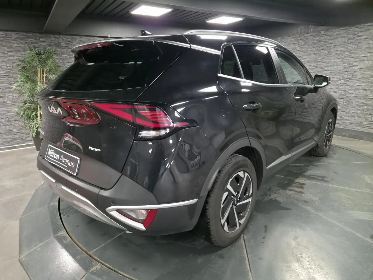 KIA SPORTAGE noir en 3/4 arrière droit, avec feux arrière LED et jantes alliage 17 pouces dans un showroom.