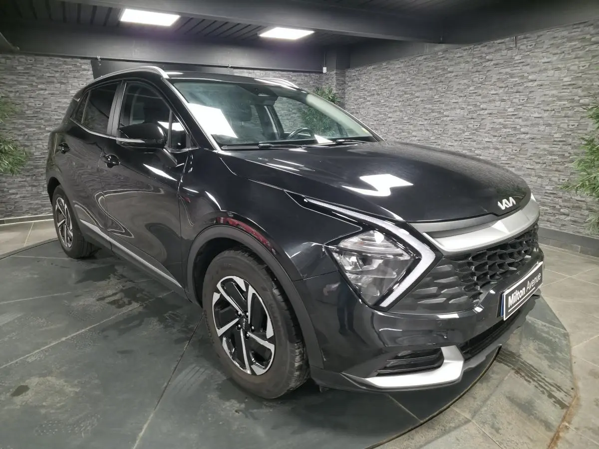 KIA Sportage noir vu en 3/4 avant droit, avec calandre noire laquée et jantes alliage 17 pouces.