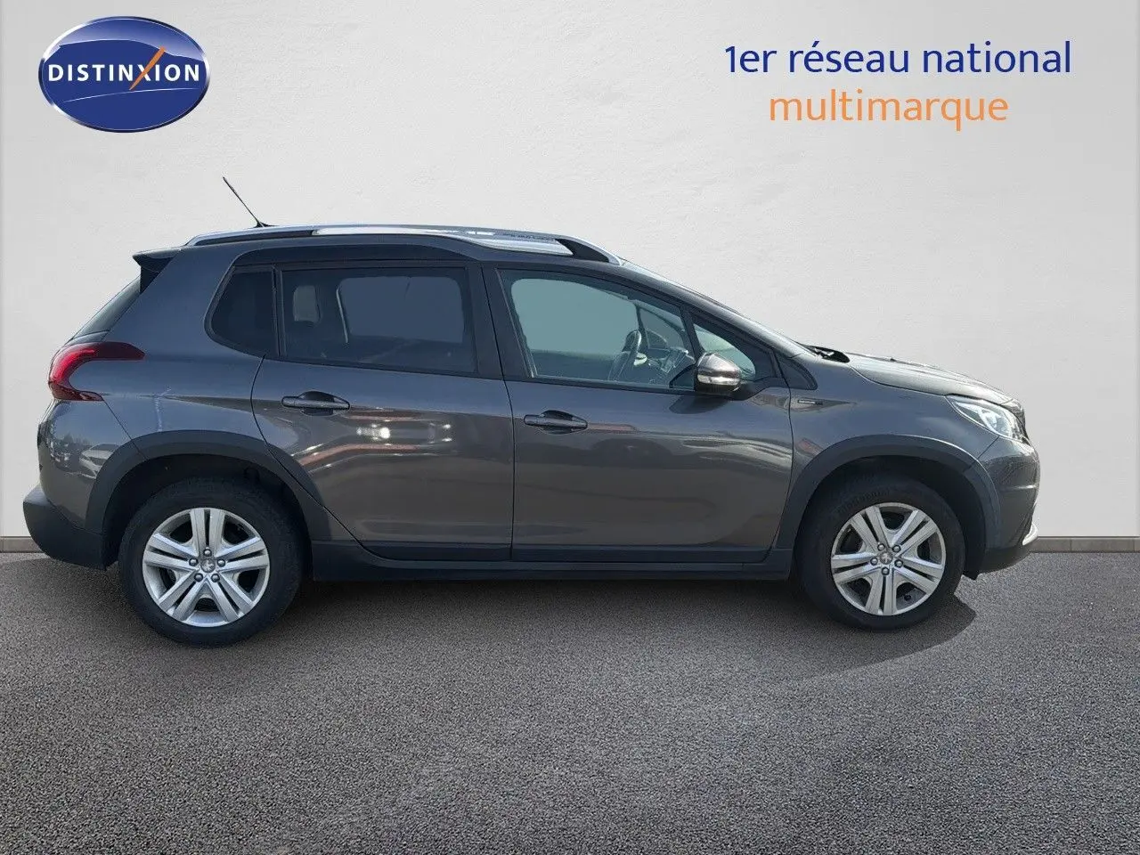 Peugeot 2008 gris platinium vue de profil côté gauche, SUV compact avec jantes alliage et barres de toit.