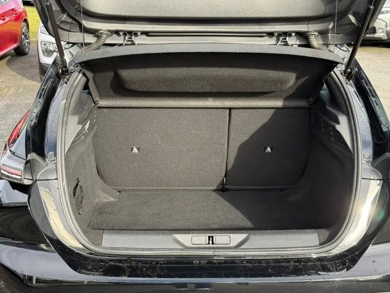 Coffre ouvert vu de l'arrière d'une Peugeot 308 2024 noir Perla Nera, montrant l'espace de chargement vide et les sièges arrière rabattables.