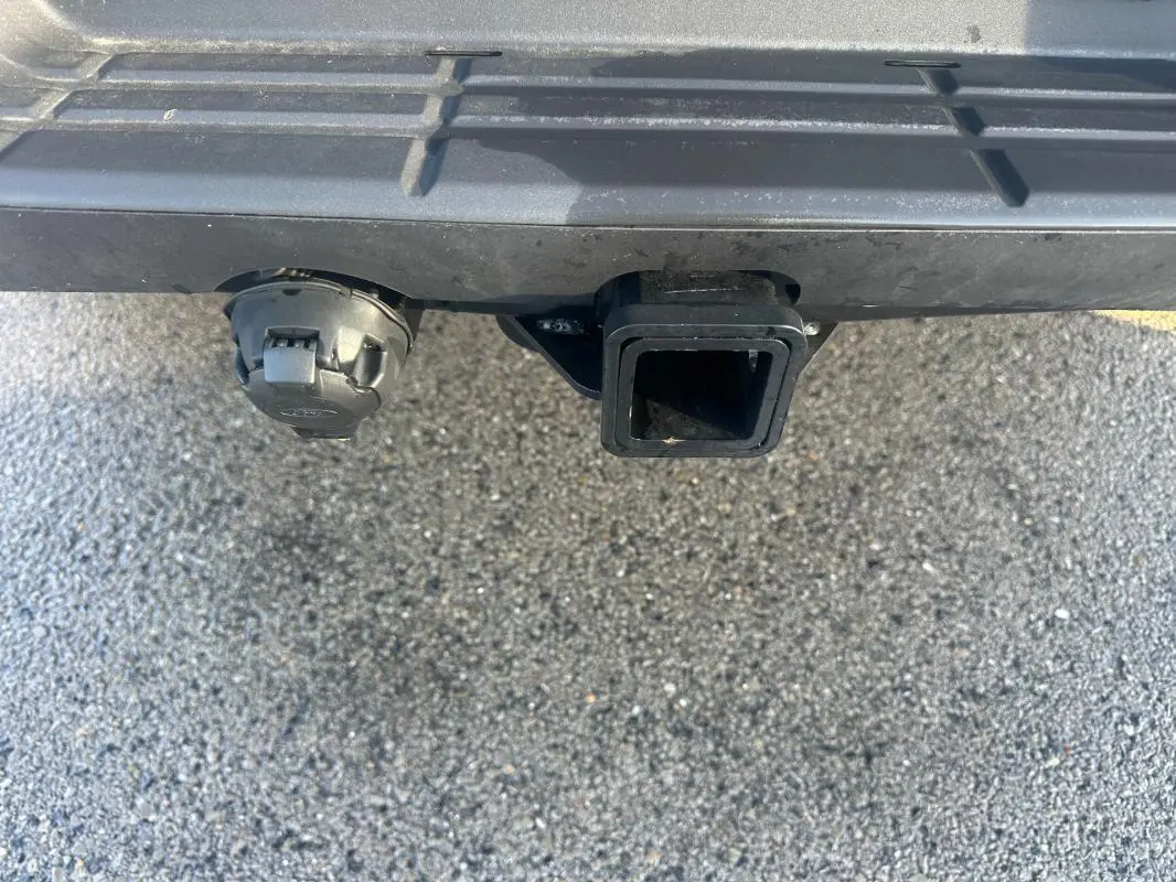 Gros plan sur l'attelage et la prise électrique sous le pare-chocs arrière noir du Ford Ranger blanc.