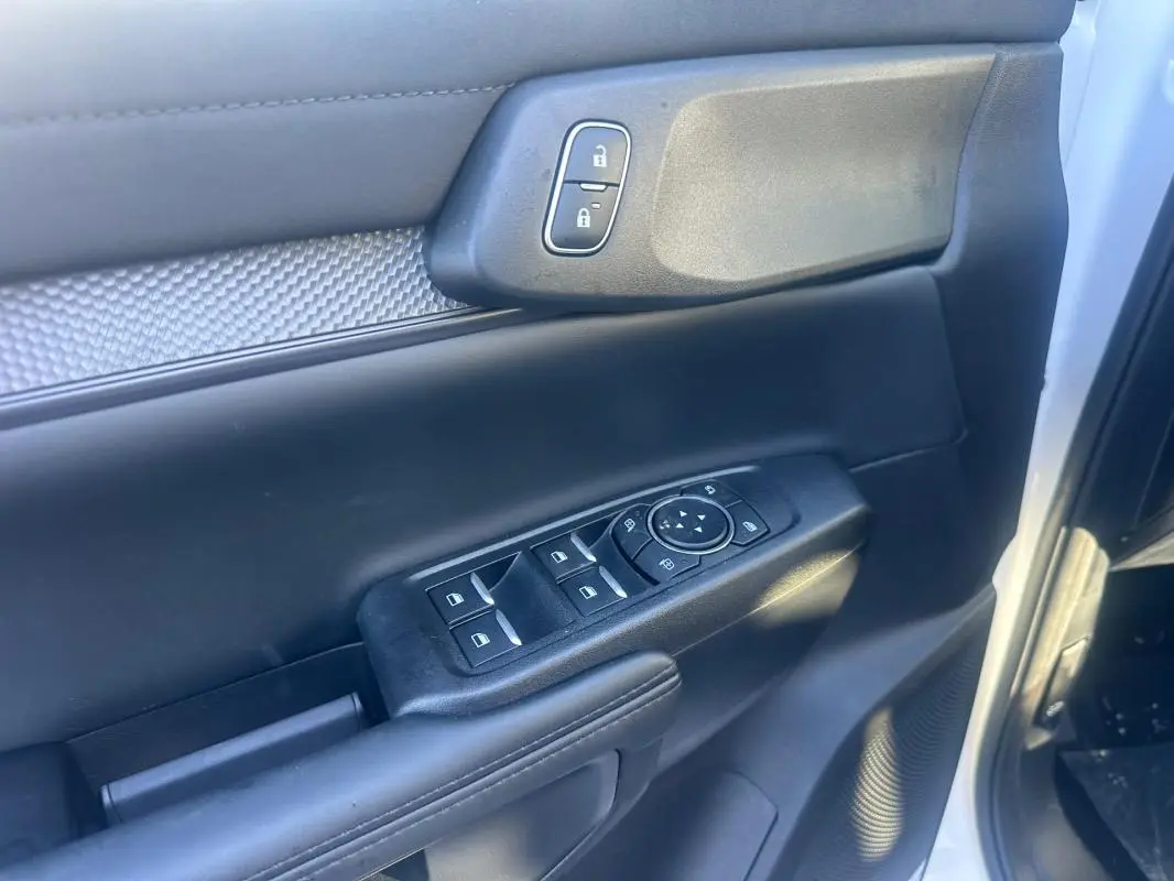 Gros plan sur la porte avant gauche du Ford Ranger blanc 2025, avec commandes des vitres et verrouillage.