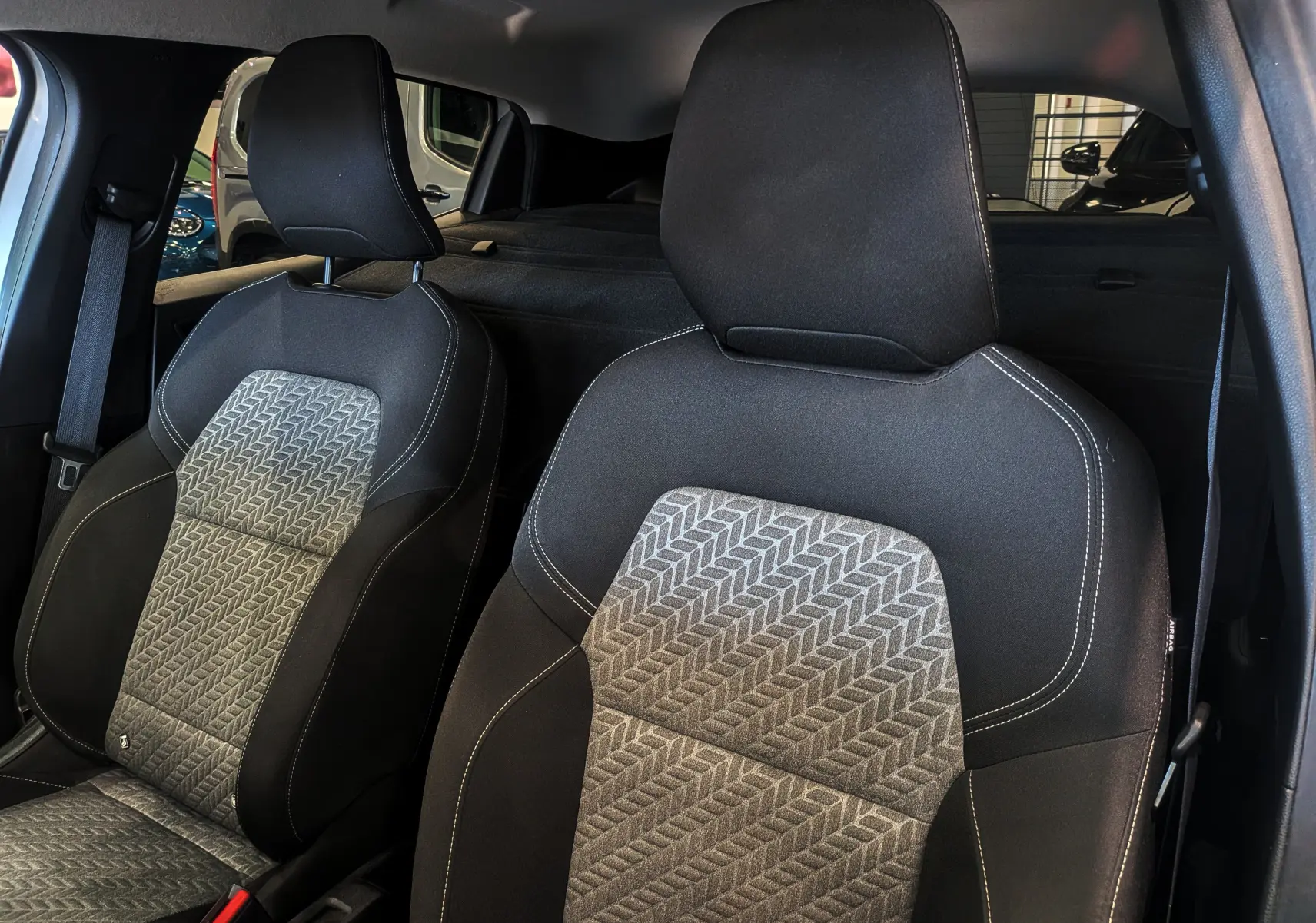 Gros plan sur les sièges avant en tissu noir et gris à motifs géométriques de la Renault Clio V Société Gris Platine.