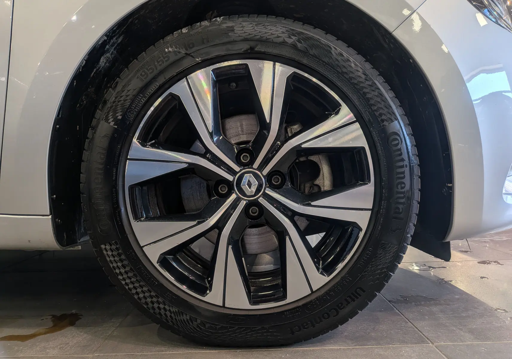 Gros plan sur la roue avant gauche gris platine d'une Renault Clio V avec jante alliage bicolore et logo central Renault.