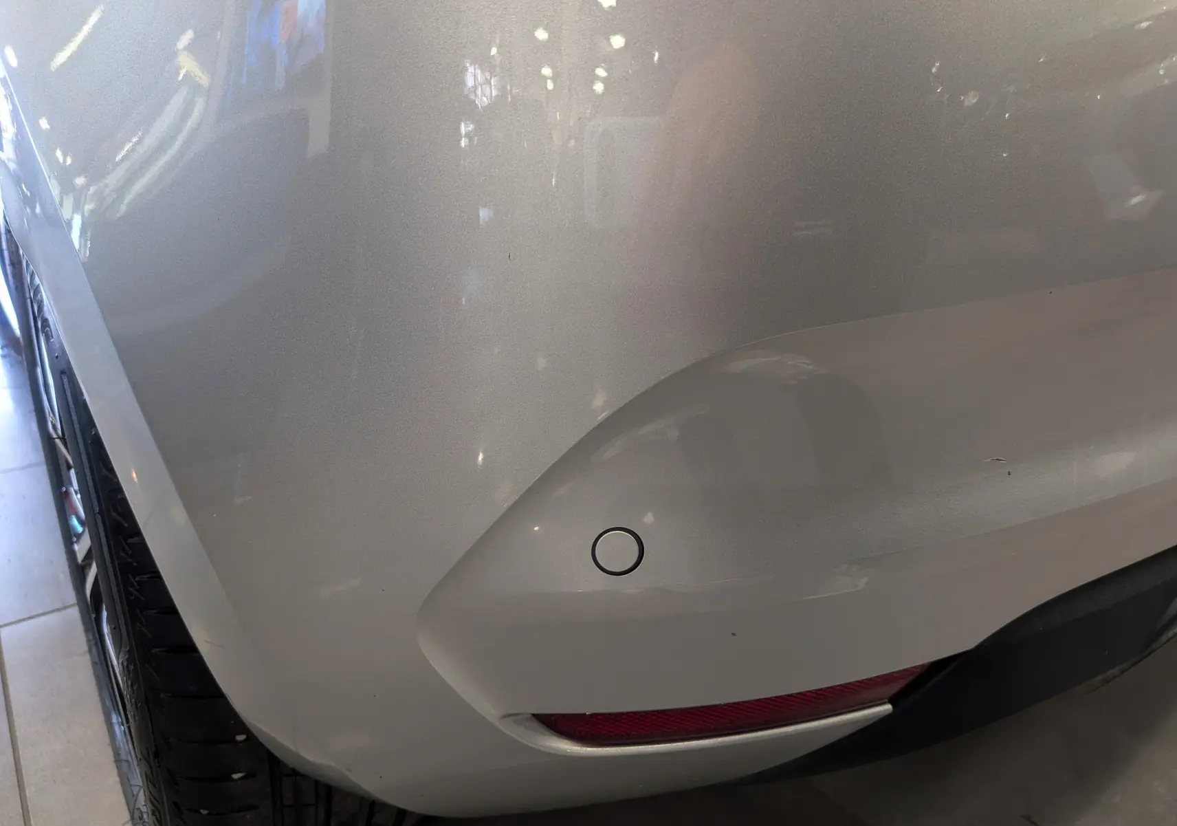 Gros plan sur l'angle arrière droit d'une Renault Clio V gris platine, avec capteur de recul et feu antibrouillard visible.