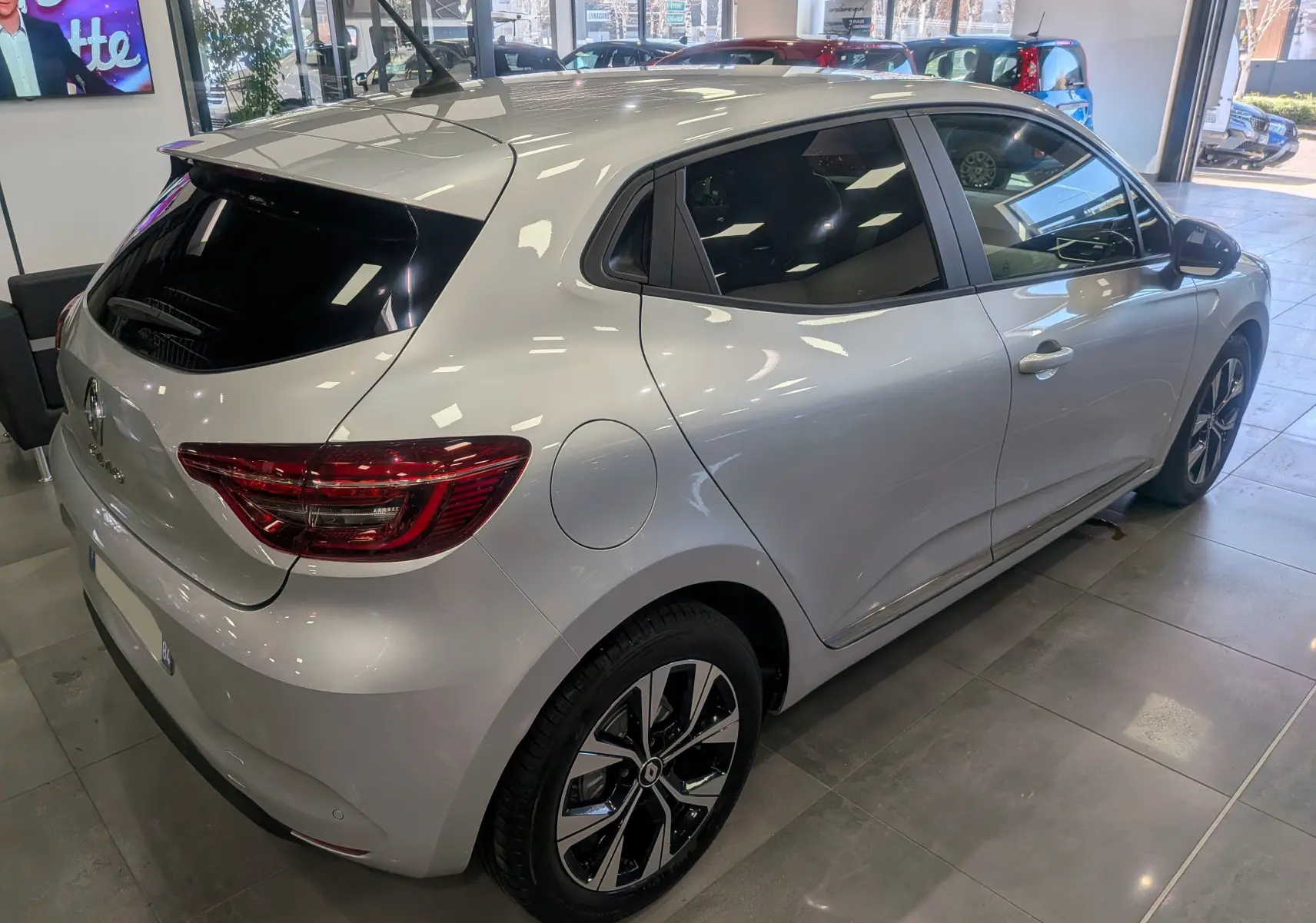 Renault Clio V gris platine vue 3/4 arrière droit, avec jantes alliage bi-ton et vitres teintées en showroom.