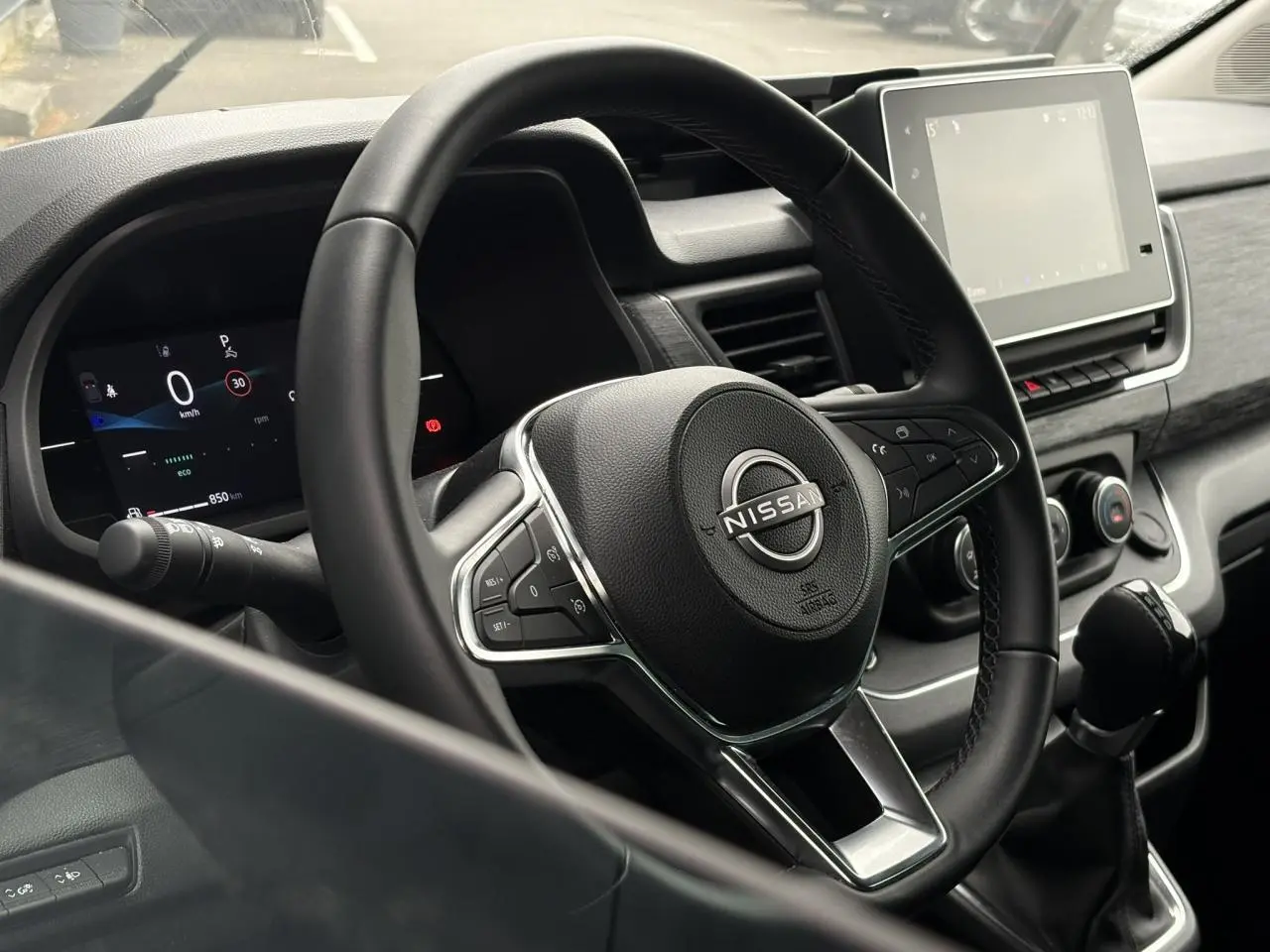 Vue intérieure rapprochée du volant noir et du tableau de bord numérique du Nissan Primastar 2025.
