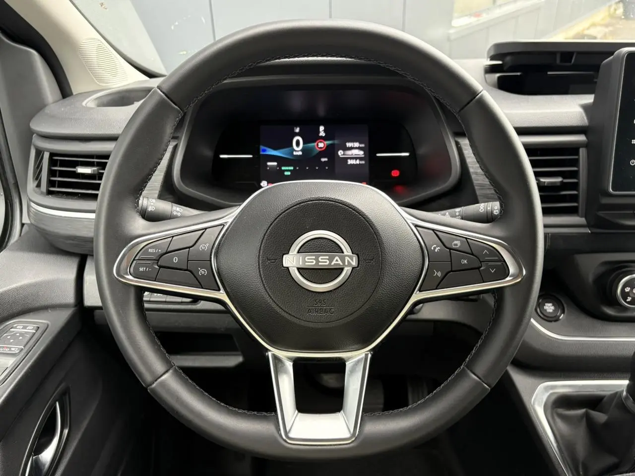 Vue rapprochée du volant noir du Nissan Primastar 2025 avec commandes intégrées et tableau de bord numérique.