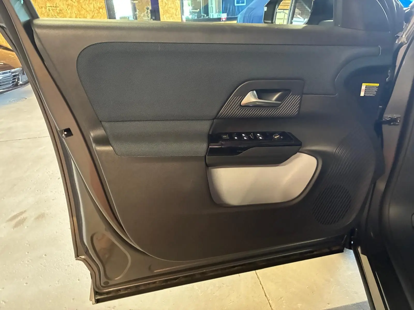 Vue intérieure de la porte arrière gauche grise du Citroën C5 Aircross 1.2 Hybride 145 Plus avec commandes de vitres et haut-parleur intégré.