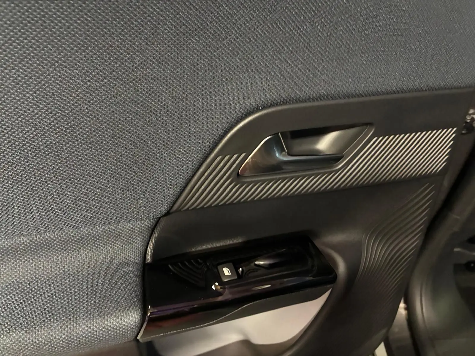 Détail de la porte intérieure côté gauche du Citroën C5 Aircross gris, avec poignée et commandes de vitre.