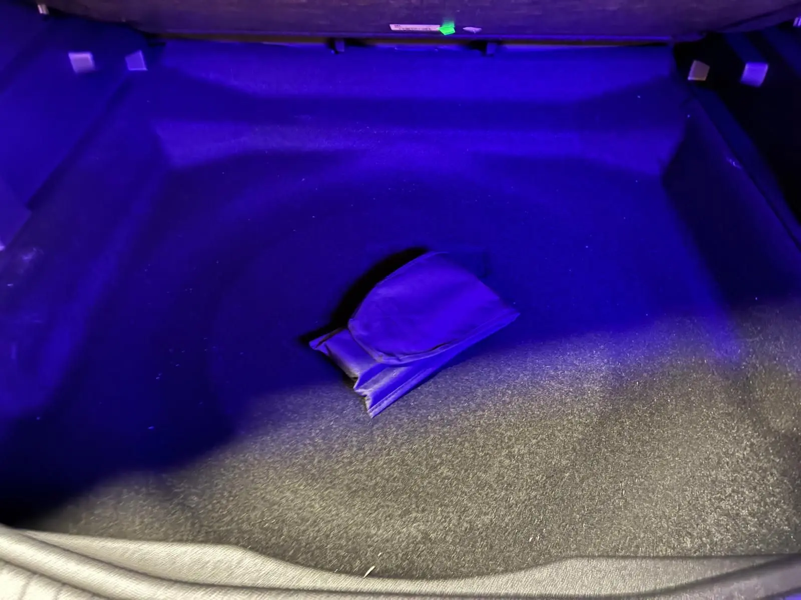 Coffre du Citroën C5 Aircross gris 2026 éclairé en bleu, montrant un rangement central avec pochette.