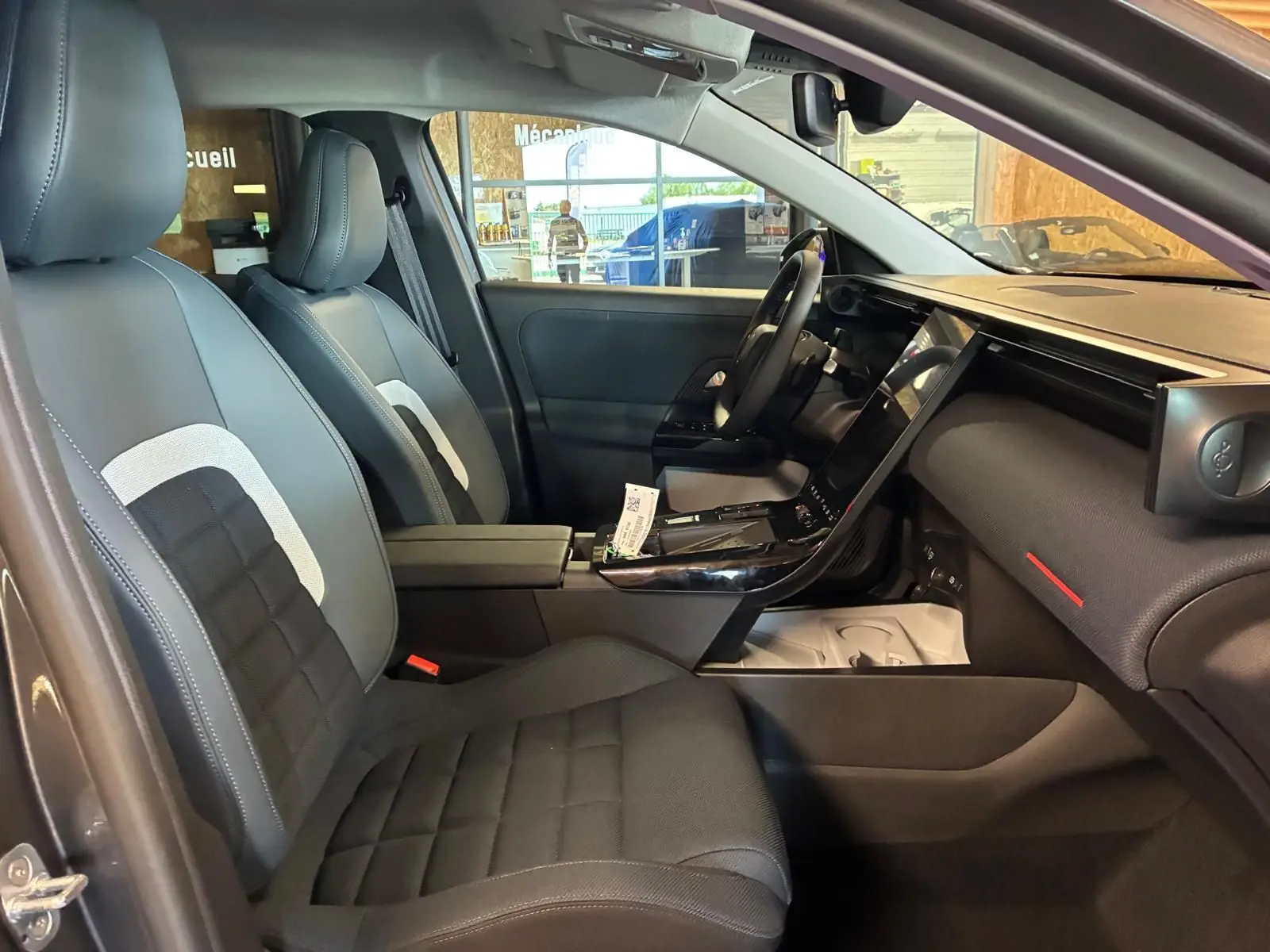 Vue intérieure côté conducteur du Citroën C5 Aircross 1.2 Hybride 145 Plus 2026 avec sièges tissu noir et tableau de bord moderne.