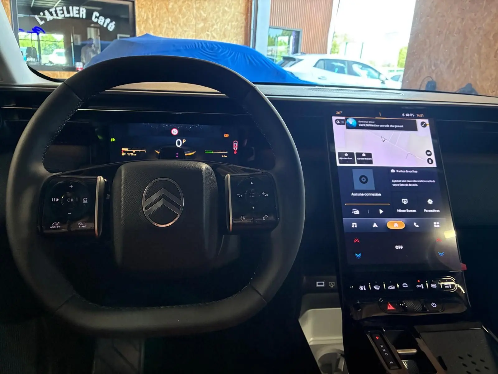 Vue intérieure centrée sur le volant noir et l’écran tactile vertical du tableau de bord du Citroën C5 Aircross gris hybride.