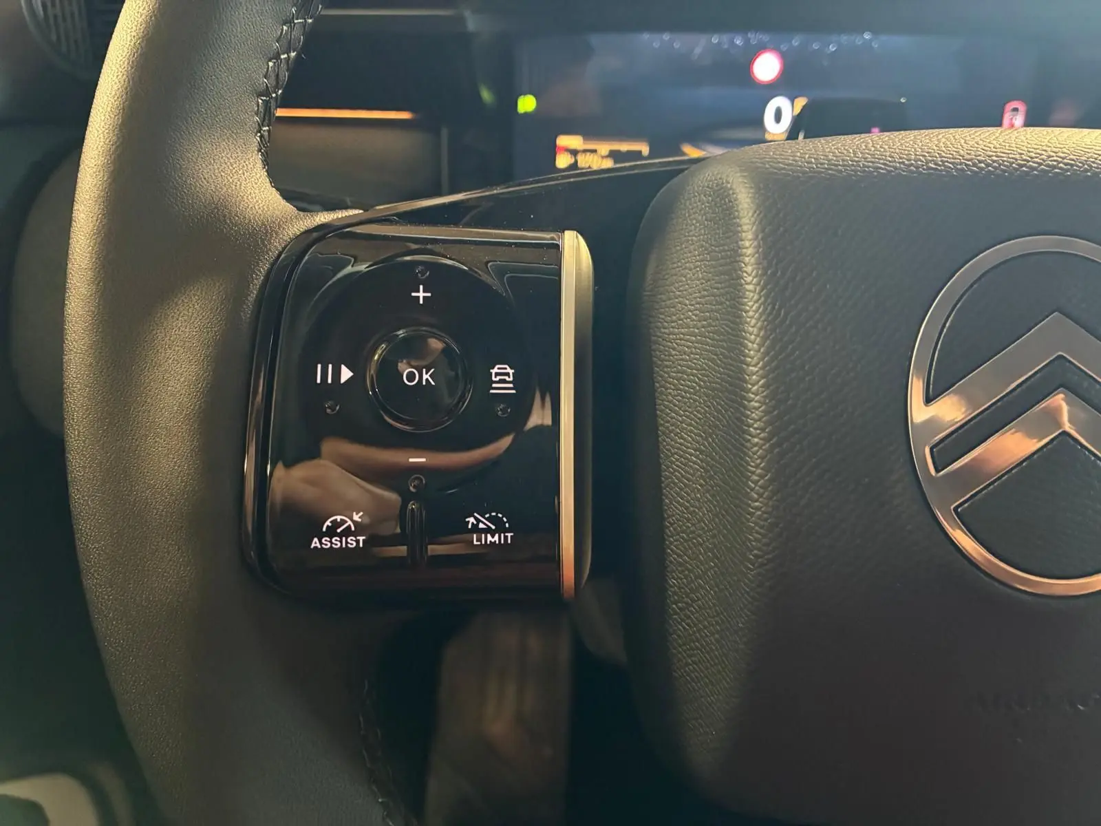 Gros plan sur la partie gauche du volant gris du Citroën C5 Aircross 1.2 Hybride 145 Plus avec commandes intégrées et logo Citroën visible.