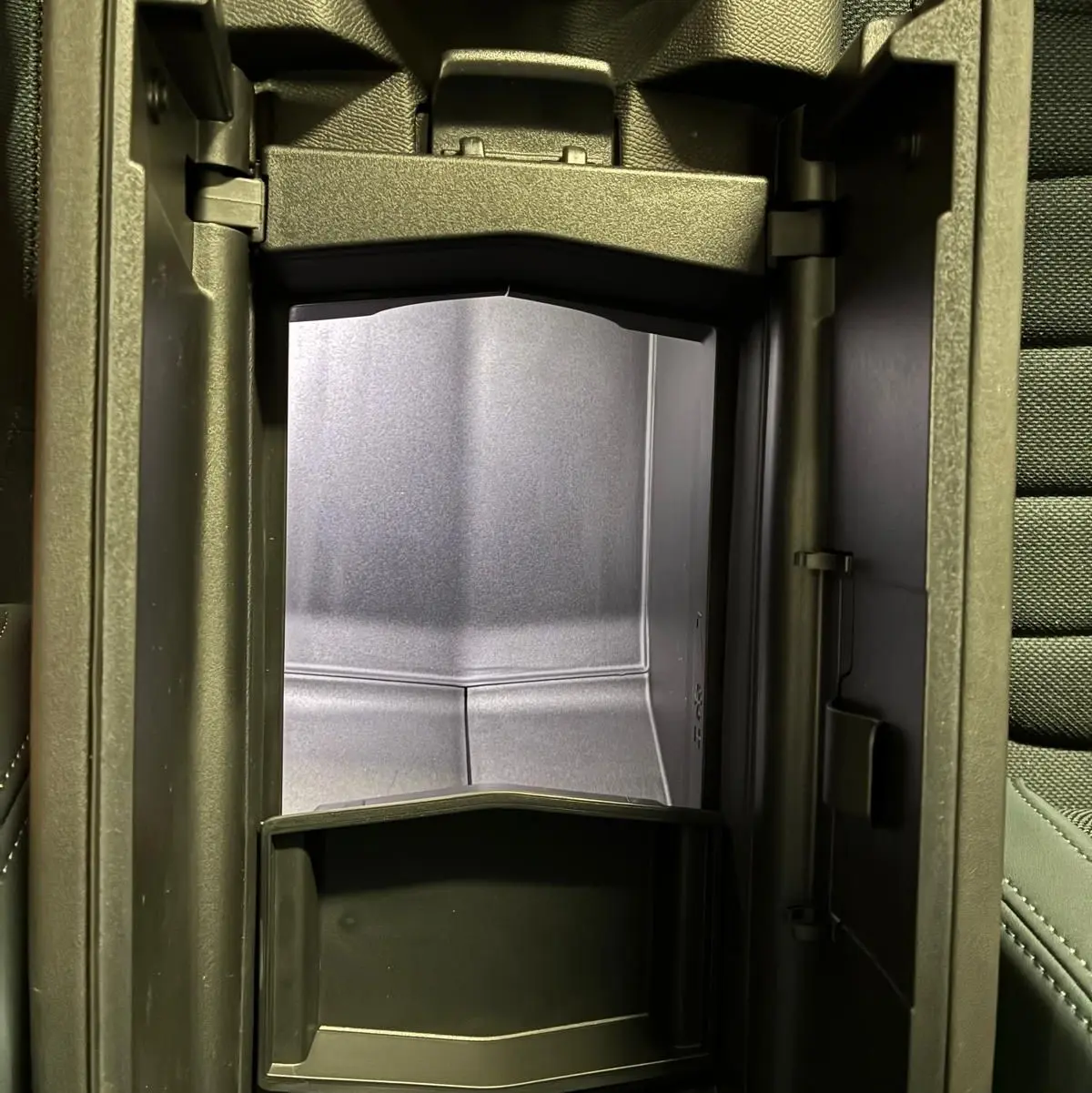 Vue rapprochée de la console centrale ouverte du Citroën C5 Aircross 1.2 Hybride 145 Plus, intérieur noir en tissu.