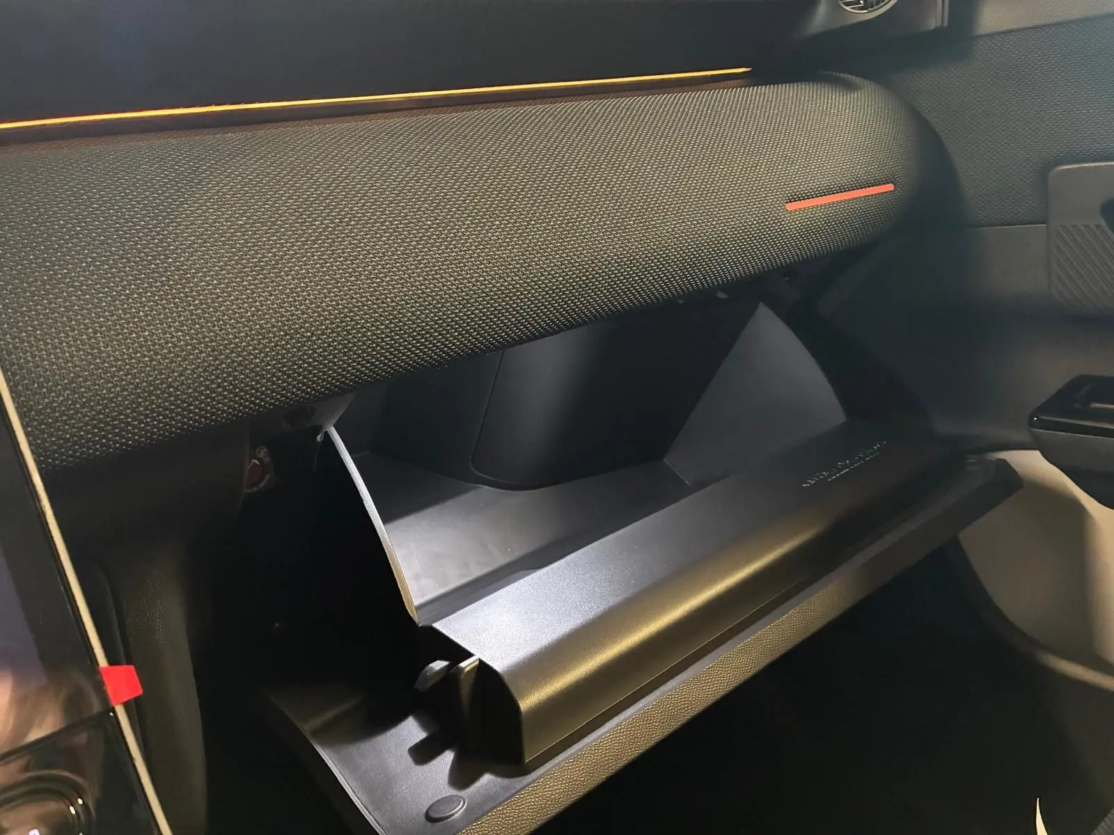 Gros plan sur la boîte à gants ouverte côté passager du Citroën C5 Aircross gris, intérieur tissu noir.